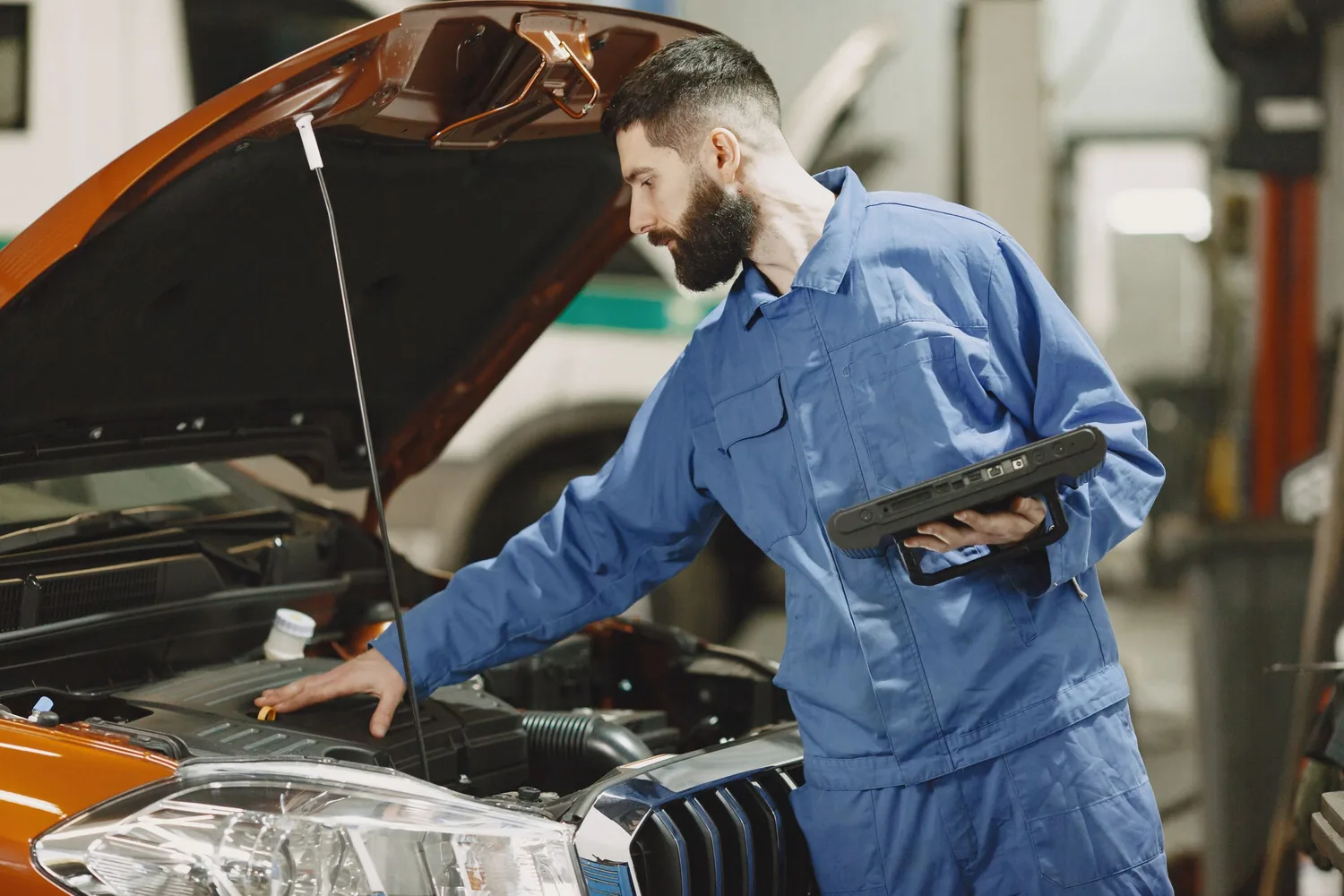 Mechaniker im Werkstattkontext an offenem Motorraum; illustratives Stockfoto.